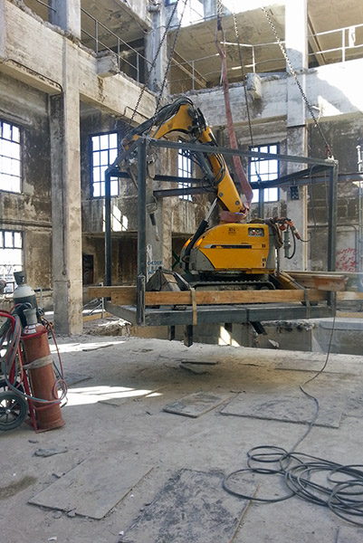Engin de chantier Brokk en train d'être installé dans une cage en métal pour des travaux de déconstruction en hauteur